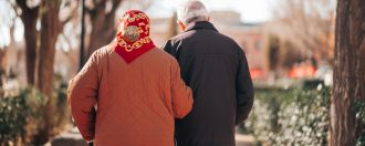 an elderly couple walking arm in arm