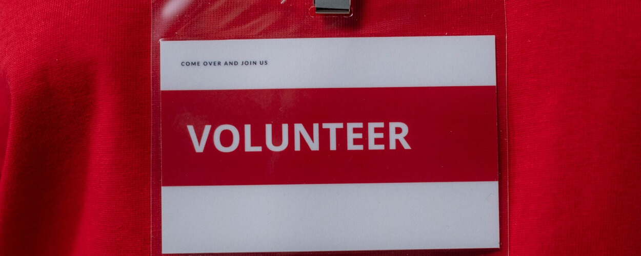 person wearing an id card telling people to try volunteering